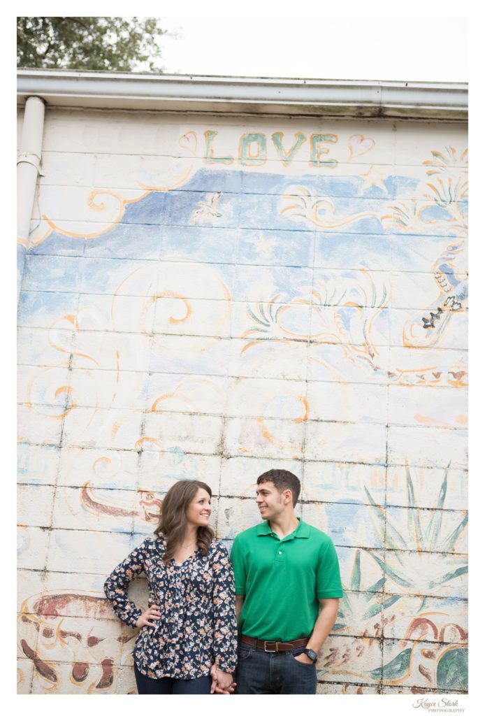 Engagement portrait in front of painted wall mural in historic downtown ocean springs