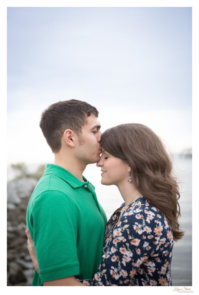 engagement photo on the beach in ocean springs with groom kissing bride to be on forehead