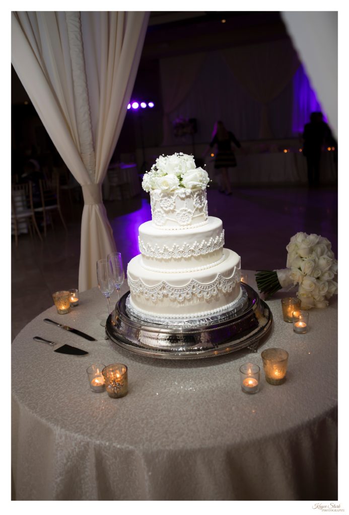 Wedding cake from French Kiss Pastries with specialty draping by Southern Event Productions with a pin light on cake for dramatic entrance into reception hall